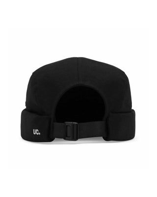 Watch caps in various colors laid out on a grassy field.