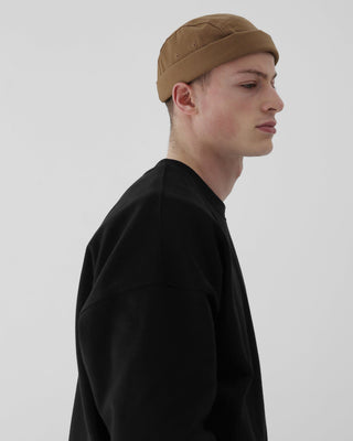 A brimless cap being packed into a travel backpack.