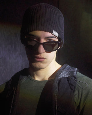 Runner in a black URH K-002 running beanie and sunglasses wearing a running pack, cold weather running gear