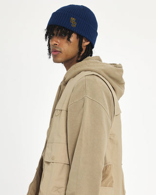 model-wearing-undercontrol-brand-denim-blue-color-knit-beanie-with-logo-photo
