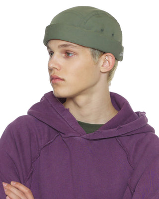 model-side-view-wearing-undercontrol-brand-green-color-brimless-hat-photo