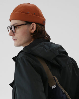 model-wearing-undercontrol-brand-brick-orange-color-brimless-cap-photo