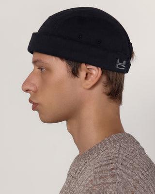 male-model-side-view-wearing-undercontrol-brand-washed-cotton-black-color-brimless-cap-photo